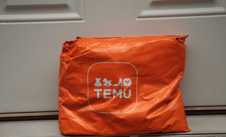 Temu Orange Rectangle Bag Package With Logo On It Delivery Delivered Leaning Against White Door, Close Up